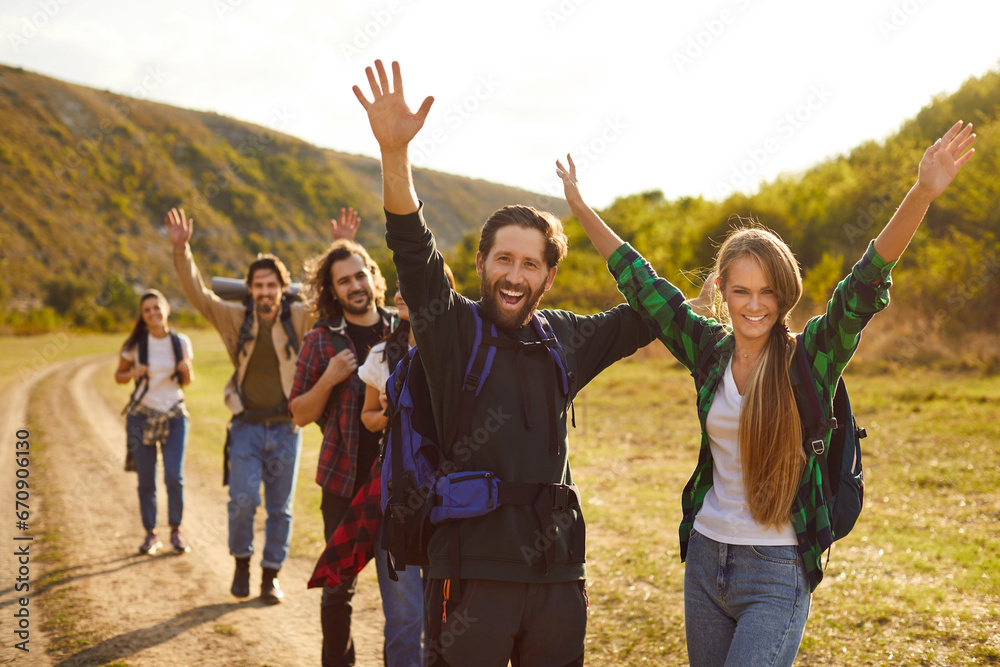 Portrait of overjoyed group of tourists having walking tour of mountains trekking with big backpacks and looking at camera. Happy smiling friends hiking in nature. Adventure and people travel concept