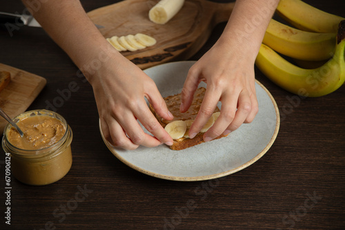 Peanut butter sandwich with banana - woman preparing breakfast.