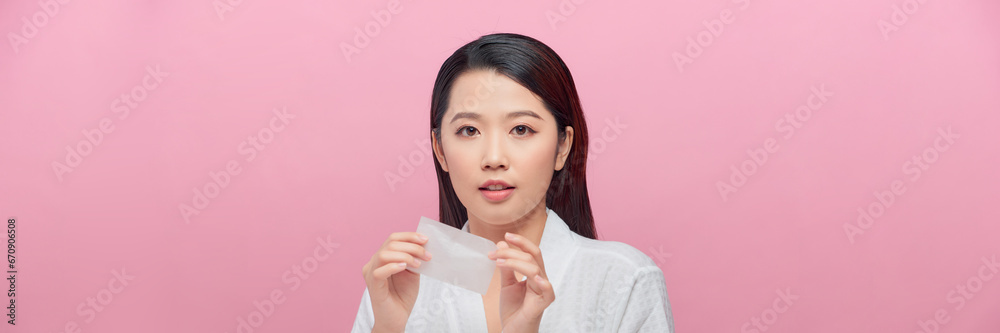 Beautiful woman using mattifying wipe on pink background Beautiful woman using mattifying wipe on pink background