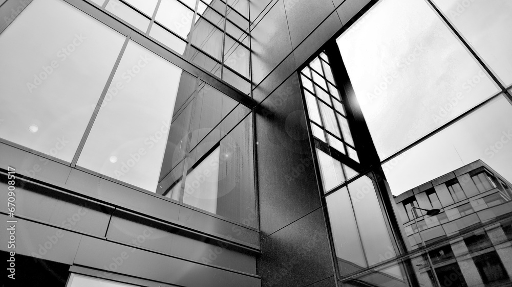 A view at a straight facade of a modern building with a dark grey facade. Dark grey metallic panel facad. Modern architectural details. Black and white. A view at a straight facade of a modern building with a dark grey facade. Dark grey metallic panel facad. Modern architectural details. Black and white.