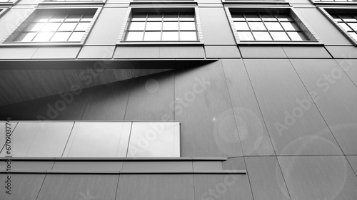 A view at a straight facade of a modern building with a dark grey facade. Dark grey metallic panel facad. Modern architectural details. Black and white.