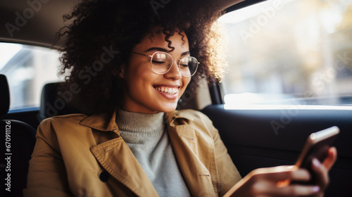 Smiling African American woman with mobile phone in car. A young black woman uses the Internet in the car. The concept of tenologies. Lifestyle.