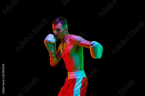 Sportsman, professional boxer, mixed martial art fighter training against over black mode background in mixed neon filter, light.