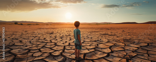 Small boy standing on dry lake or land. enviroment concept. cracked earth panorama photo. photo