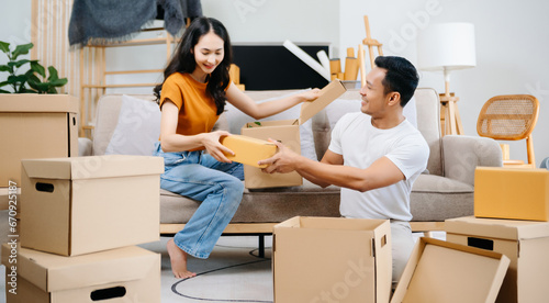 Asian young attractive couple man and woman use tablet and smartphone online shopping furniture decorate house with carton package move in new house. Young married asian moving home. .