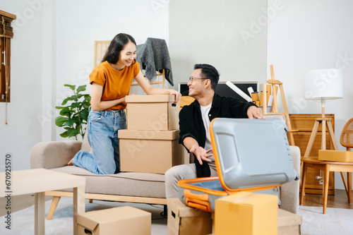 Young couple with big boxes moving into a new house, new apartment for couple, young man and woman helping to lift boxes on sofa for the new home, Moving house..