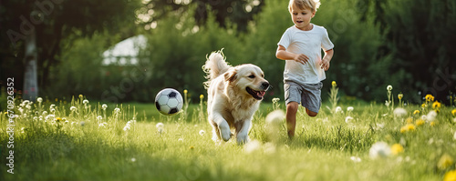 Young boy playing soccer with his dog on green grass. #670926352