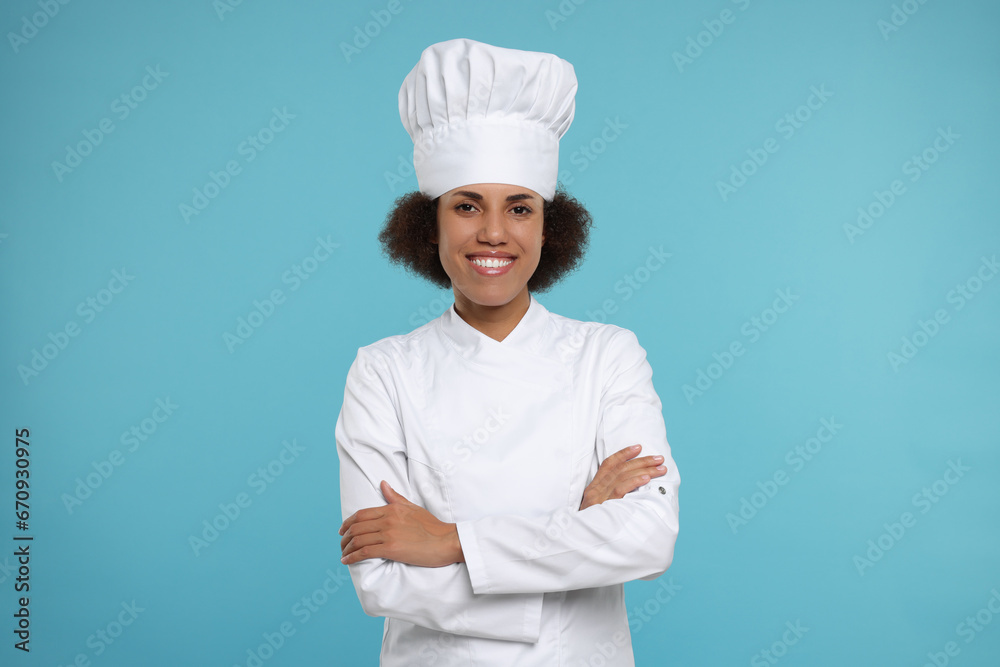 Portrait of happy female chef in uniform on light blue background Portrait of happy female chef in uniform on light blue background