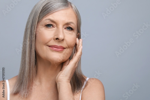 Portrait of beautiful senior woman on grey background. Space for text