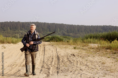 Man with hunting rifle outdoors. Space for text