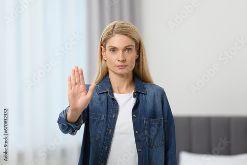 Woman showing stop gesture in light room