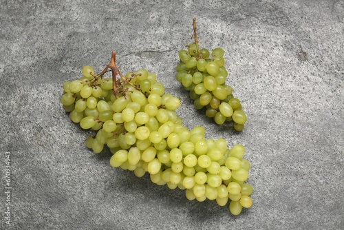 Delicious fresh green grapes on grey textured table, top view