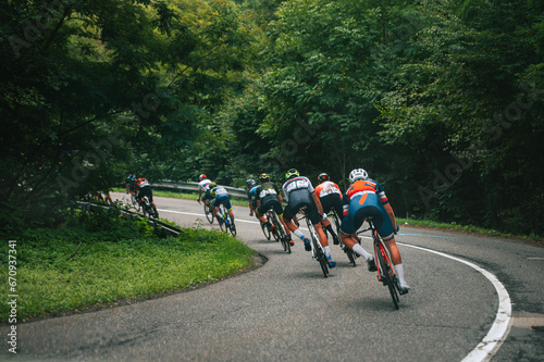 Downhill in professional cycling race. Athletes in green summer nature on the road photo