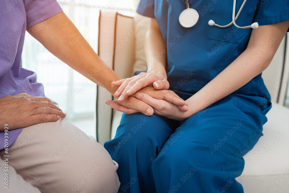 Closeup young nurse taking care and talking mature female patient sitting on sofa in hospital. Healthcare concept. Closeup young nurse taking care and talking mature female patient sitting on sofa in hospital. Healthcare concept.