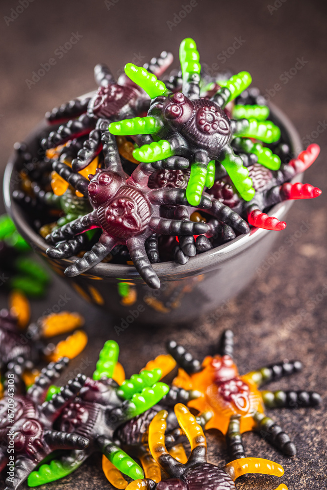Fototapeta premium Scary sweet jelly spiders. Halloween candies in bowl on black table.