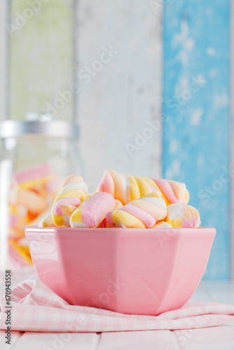 Sweet colorful marshmallows in bowl on white kitchen table.