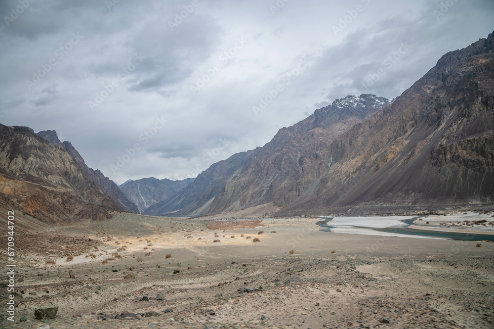 Valley between mountains on a cloudy day. A Dried river trains of Shyok river in Nubra Valley in Ladakh Region of Indian Himalayan territory .A Barren landscape of Cold dessert in Himalaya Valley . Valley between mountains on a cloudy day. A Dried river trains of Shyok river in Nubra Valley in Ladakh Region of Indian Himalayan territory .A Barren landscape of Cold dessert in Himalaya Valley .