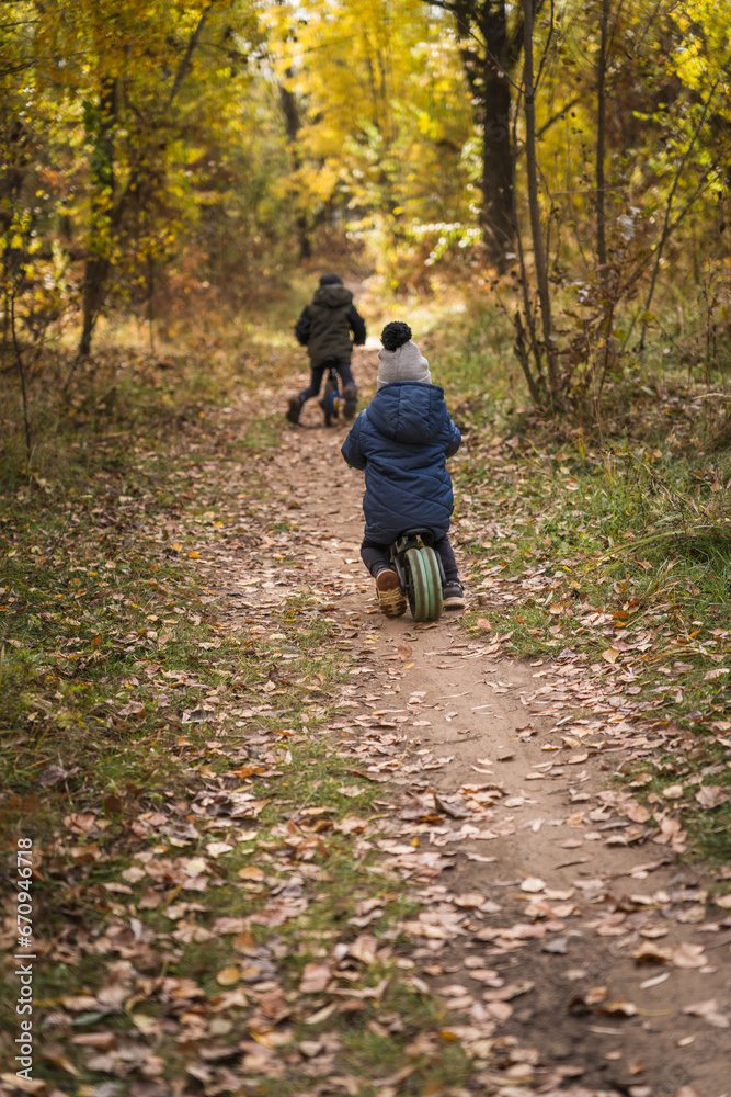 Fototapeta premium Family walking with kids in the autumn forest with yellow bright leaves