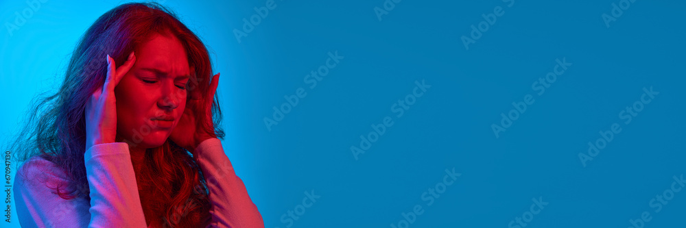 Irritation. Young girl holding hands on head, having deadlines against blue studio background in neon light. Stress. Concept of youth, human emotions, facial expression, lifestyle - obrazy, fototapety, plakaty 