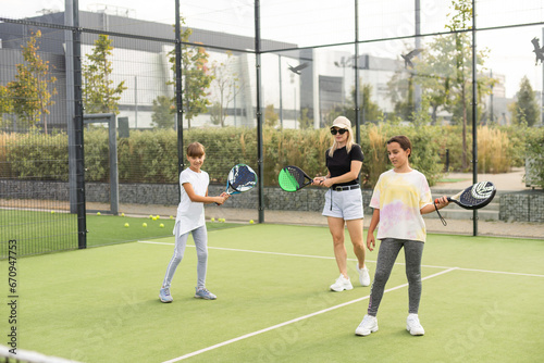 mother and daughters playing padel outdoor © Angelov