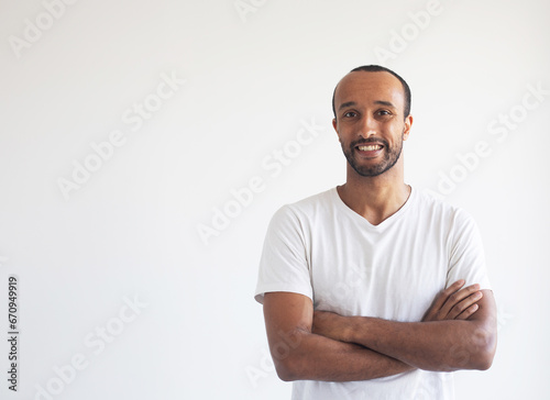 Portrait of young afro american man standing with arms crossed against white background