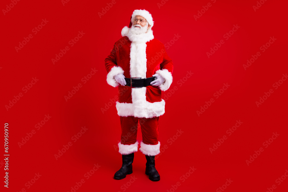 Full length photo of good mood santa claus fairy charcter look up empty space special new year offer isolated on red color background Full length photo of good mood santa claus fairy charcter look up empty space special new year offer isolated on red color background