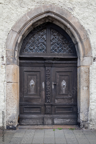 Old decorative wooden entrance door to the church. Large wooden arched gates with carved details, decorative metal elements and handles
