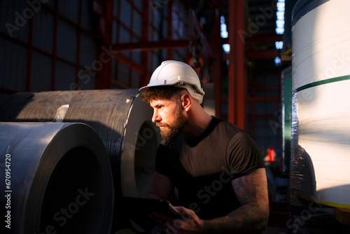 Blue collar worker work at metal sheet factory.