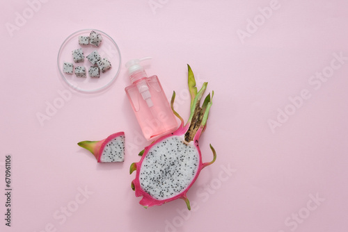 Fototapeta Naklejka Na Ścianę i Meble -  Dragon fruit cubes in a clear petri dish, accompanied by a toner bottle filled with dragon fruit extract, set against a soft pastel backdrop. Explore vegan cosmetics infused with tropical fruit.