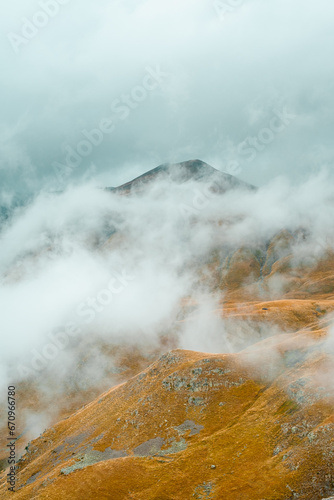 Foggy mountain peaks on Col De La Bonette. Autumn colors. Mountain roads in the French Alps.