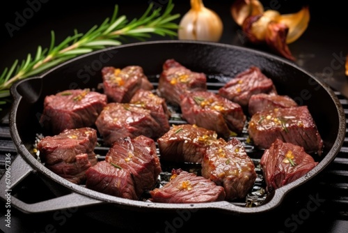 grilled steak tips with garlic chunks on a black frying pan