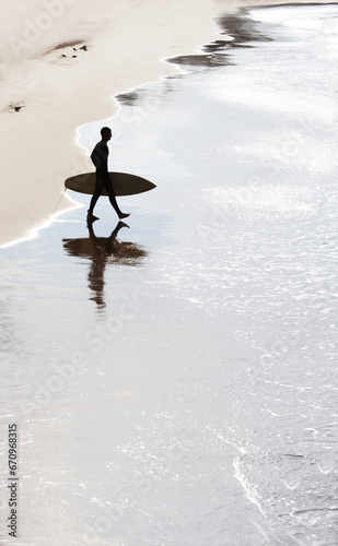 Bild auf Leinwand Silhouette of surfer going to riding in water of Bay of Biscay in shiny wet sand