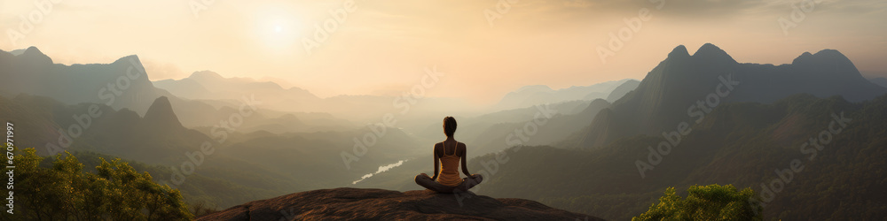 Woman sitting on hilltop, meditating amongst the misty graduating hills, while Sun is setting.