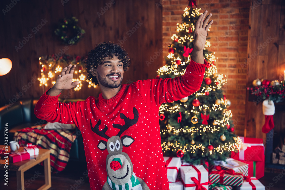 Photo portrait of energetic active guy dancing raised hands up on merry christmas theme party indoors house decorated garlands background