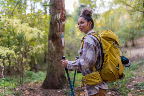 A curly-haired forest wanderer  enjoying the serene atmosphere of an autumn forest trail  accompanied by her trusty binoculars.
