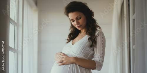 Pregnant mother in white dress, caressing her bump.