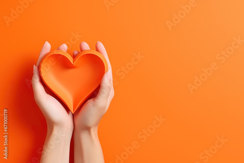 hand holds a heart love shape on an orange background with copy space