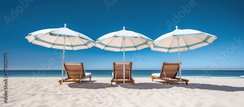 Beach chairs and umbrellas on sandy beach on tropical beach with clear blue sky