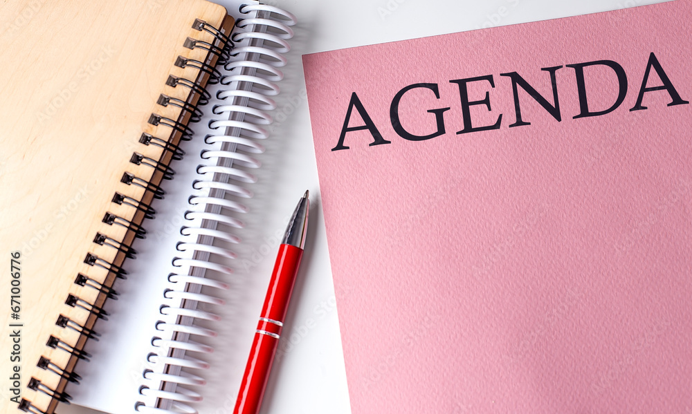 AGENDA word on the pink paper with office tools on white background