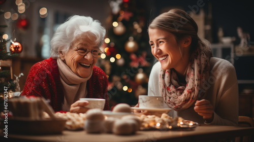 Happy grandmother drinking tea with granddaughter  Christmas tree at home