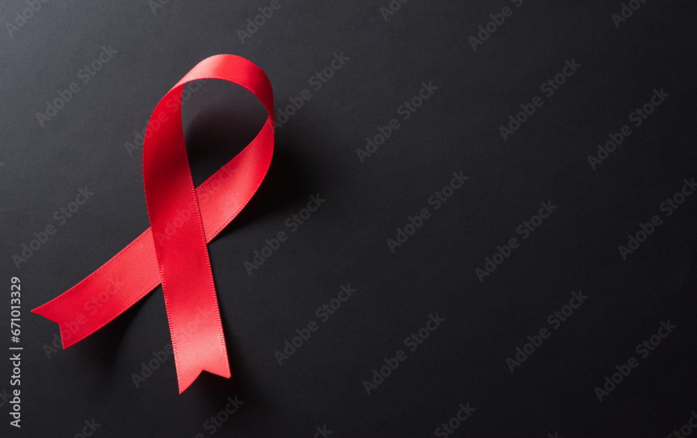 Closeup red ribbon HIV, world AIDS day awareness ribbon on black background. Healthcare and medicine concept. - obrazy, fototapety, plakaty 