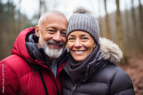 Middle age cheerful couple enjoying outdoors activity in winter forest