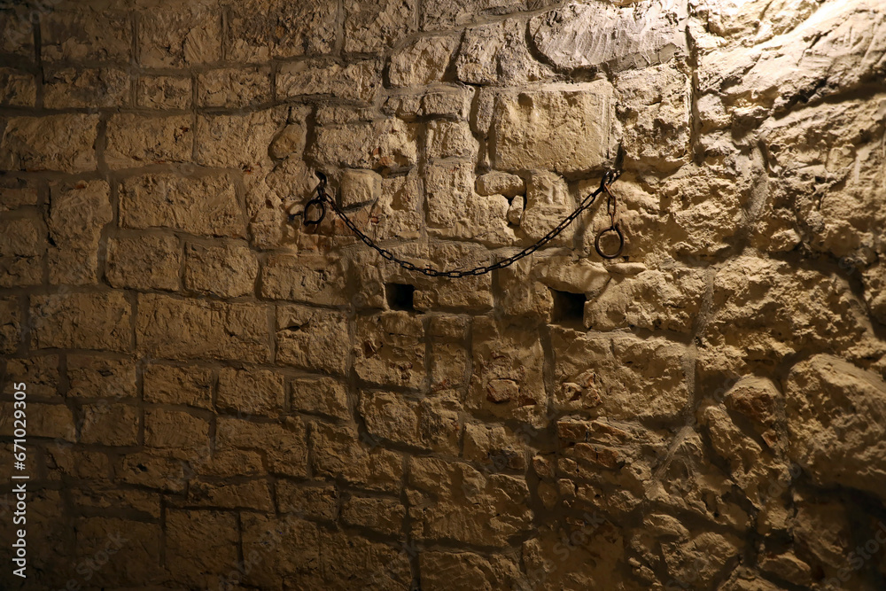 Slavery and bondage strong steel old shackles on stone wall in castle cellar or tomb Slavery and bondage strong steel old shackles on stone wall in castle cellar or tomb