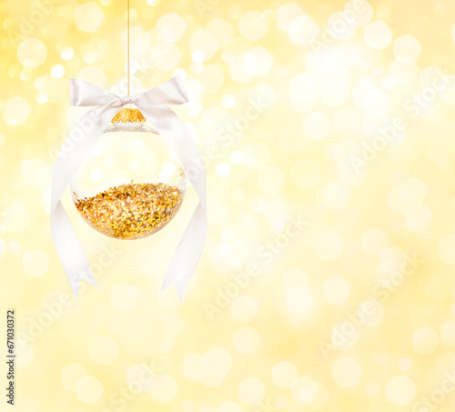 Christmas ball with white ribbon on bokeh background. New Year greeting card.