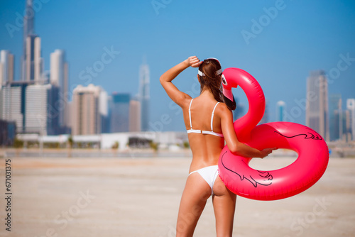 Tanned model woman in bikini. Beach and skyscrapers. UAE, Dubai