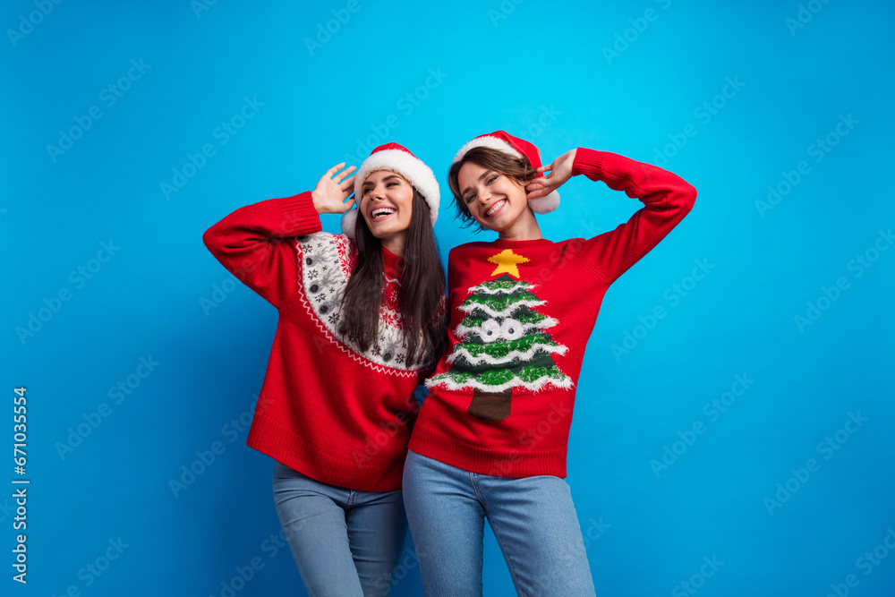 Photo of two holly jolly girls celebrate new year dance on event occasion isolated blue color background