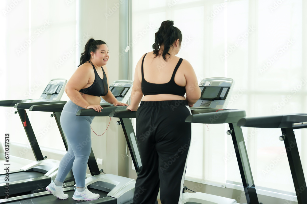 Two overweight Asian women, friends determined to exercise to lose weight, invited each other to run on the treadmill in the village club gym during their free time. Concept Lifestyle and exercise Two overweight Asian women, friends determined to exercise to lose weight, invited each other to run on the treadmill in the village club gym during their free time. Concept Lifestyle and exercise