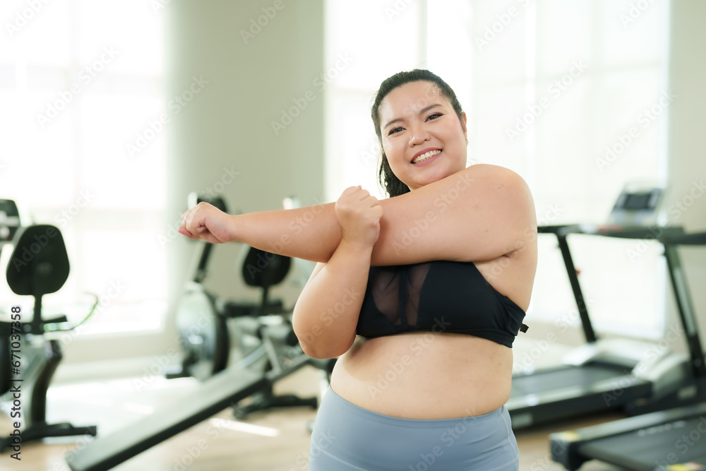 Beautiful overweight Asian woman does light exercise by stretching her arms and twisting her arms around after running and lifting dumbbells to relax during a time when she wants to lose weight. Beautiful overweight Asian woman does light exercise by stretching her arms and twisting her arms around after running and lifting dumbbells to relax during a time when she wants to lose weight.