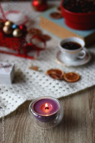 Various colorful Christmas decorations, soft blanket, cup of tea, sweet snacks and lit candles on the table. Cozy Christmas atmosphere at home. Selective focus.