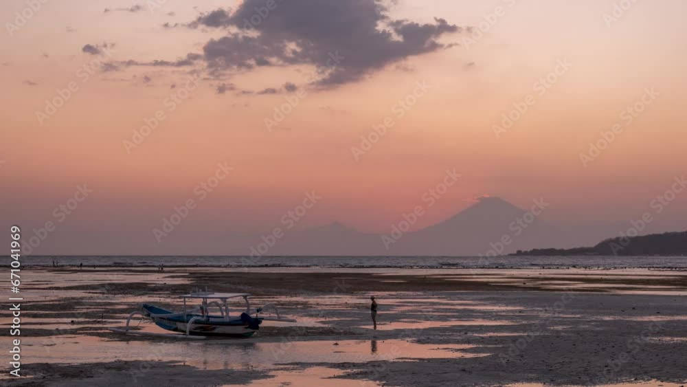 Beautiful tropical sunset time lapse at the ocean with fishing boat and volcano mount Agung in Gili Air Lombok Indonesia, rising tide Beautiful tropical sunset time lapse at the ocean with fishing boat and volcano mount Agung in Gili Air Lombok Indonesia, rising tide